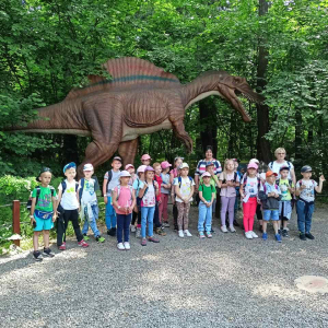 Uczniowie kl. I wraz z wychowawczyniami w Parku Dinozaurów w Zatorlandzie. W tle stojąca makieta dinozaura. Kliknięcie na zdjęcie spowoduje powiększenie go do rozmiarów oryginalnych.