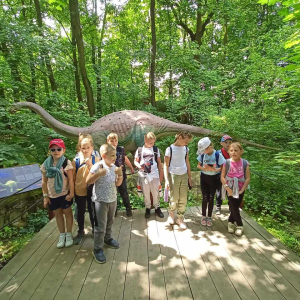 Uczniowie kl. I b w Parku Dinozaurów w Zatorlandzie. W tle makieta dinozaura. Kliknięcie na zdjęcie spowoduje powiększenie go do rozmiarów oryginalnych.