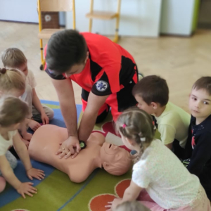 Przedszkolaki z oddziału przedszkolnego w Rudy Rysiu. Dzieci ćwiczą udzielanie pierwszej pomocy na fantomie. W tle interaktywna tablica. Klinięcie na zdjęcie spowoduje jego powiększenie do rozmiaru oryginalnego.