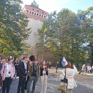 Uczestnicy wycieczki do Krakowa przed Bramą Floriańską. Uczniom Zespołu Szkół w Szczurowej towarzyszy przewodniczka oraz nauczyciele p. Karolina Góra i Katarzyna Biedrońska. Młodzież ubrana w jesienne ubrania, na plecach ma plecaki. Kliknięcie na zdjęcie spowoduje jego powiększenie do rozmiaru oryginalnego.