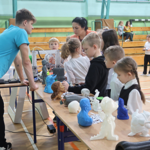 Uczniowie kl. I-III uczestniczą w warsztatach z druku 3D w hali Zespołu Szkół w Szczurowej. Towarzyszy im instruktor. Kliknięcie na zdjęcie spowoduje jego powiększenie do rozmiaru oryginalnego.