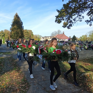 Uczennice Zespołu Szkół w Szczurowej niosą przygotowane przez siebie wiązanki na groby żołnierskie na Cmentarzu w Szczurowej. Kliknięcie na zdjęcie spowoduje jego powiększenie do rozmiaru oryginalnego.