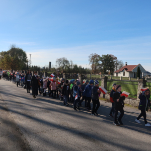 Uczniowie kl. 6b idą na czele uroczystego marszu z okazji Narodowego Święta Niepodległości. Chłopcy niosą biało-czerwony transparent z napisem "11 listopada Marsz dla Niepodległej" za nimi uczniowie kl. 4a,b niosą długą biało-czerwoną flagę oraz pozostali uczestnicy marszu. Kliknięcie na zdjęcie spowoduje jego powiększenie do rozmiaru oryginalnego.