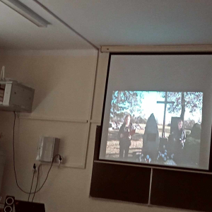 Rozwijany ekran z wyświetlonym filmem dotyczącą 80 rocznicy zamordowania  Romów w Szczurowej. Wyświetlany jest w PSP w Zaborowie. Film przygotowany przez uczniów Zespołu Szkół w Szczurowej. Kliknięcie na zdjęcie spowoduje jego powiększenie do rozmiaru oryginalnego.