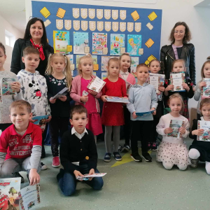 Laureaci i osoby wyróżnione w Szkolnym Konkursie Czytelniczym "Moja ulubiona książeczka". Towarzyszą im pani Dyrektor Joanna Ozorka-Krawczyk oraz bibliotekarka Marcelina Pajor. W tle dekoracja z kolorowymi pracami dzieci. Kliknięcie na zdjęcie spowoduje jego powiększenie do rozmiaru oryginalnego.