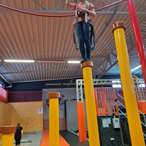 Dzieci stoją na specjalnych walcach w parku trampolin.  Kliknięcie na zdjęcie spowoduje jego powiększenie do rozmiaru oryginalnego.