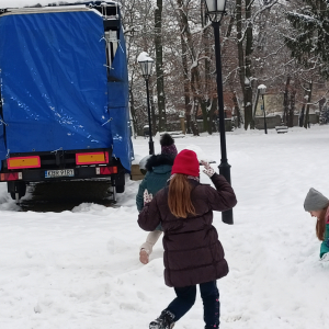 Dziewczynki i chłopcy kl. 3 b ubrani w zimowe ubrania i czapki zjeżdżają z górki po śniegu w parku w Szczurowej. Dzieci bawią się śniegiem. Kliknięcie na zdjęcie spowoduje jego powiększenie do rozmiaru oryginalnego.