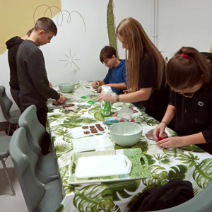 Uczniowie kl. 7 a pochyleni nad tacami z piernikami dekorują je kolorowymi pisakami i ozdobnymi cukierkami. Kliknięcie na zdjęcie spowoduje jego powiększenie do rozmiaru oryginalnego.