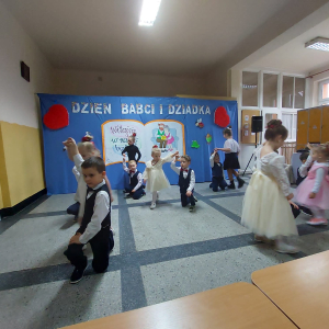 Dzieci tańczą na przedstawieniu z okazji Dnia Babci i Dziadka w Rudym Rysiu. W tle dekoracja. Kliknięcie na zdjęcie spowoduje jego powiększenie do rozmiaru oryginalnego.