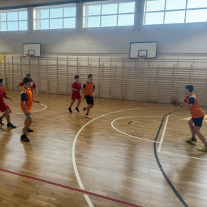 Młodzież z Zespołu Szkół w Szczurowej gra w koszykówkę. Chłopcy biegają za piłką w hali sportowej Szkoły Podstawowej w Strzelcach Wielkich. Kliknięcie na zdjęcie spowoduje jego powiększenie do rozmiaru oryginalnego.