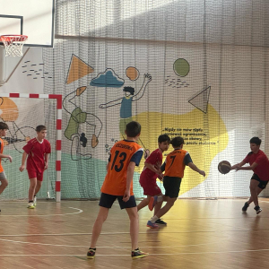 Chłopcy z Zespołu Szkół w Szczurowej grają na zawodach w Strzelcach Wielkich w koszykówkę. Ubrani są w pomarańczowe stroje sportowe. Kliknięcie na zdjęcie spowoduje jego powiększenie do rozmiaru oryginalnego.
