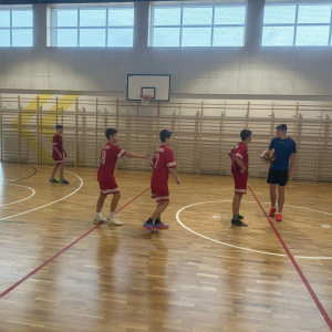 Młodzież z Zespołu Szkół w Szczurowej gra na zawodach w Szkole Podstawowej w Strzelcach Wielkich. Chłopcy biegają i grają w koszykówkę. Kliknięcie na zdjęcie spowoduje jego powiększenie do rozmiaru oryginalnego.
