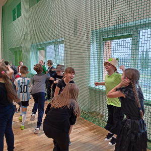 Uczniowie kl. 2 i 3 tańczą na szkolnej sali gimnastycznej. Dzieci uczestniczą w zabawie karnawałowej.  Kliknięcie na zdjęcie spowoduje jego powiększenie do rozmiaru oryginalnego.