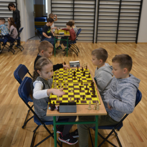 Uczniowie kl. 1-3 grają w szachy na sali gimnastycznej. Dzieci rywalizują w turnieju szachowym. Kliknięcie na zdjęcie spowoduje jego powiększenie do rozmiaru oryginalnego.