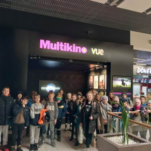Uczniowie kl. 5 a i b stoją przed kinem w Tarnowie. Towarzyszą im nauczyciele. Kliknięcie na zdjęcie spowoduje jego powiększenie do rozmiaru oryginalnego.
