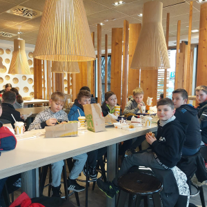Uczniowie siedzą w restauracji McDonalds i jedzą zamówione jedzenie. Uczennice siedzą przy stolikach i jedzą posiłek w McDonalds. Kliknięcie na zdjęcie spowoduje jego powiększenie do rozmiaru oryginalnego.