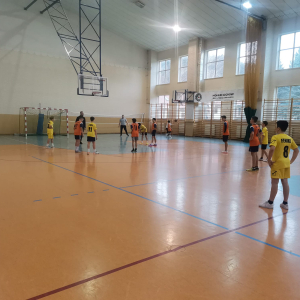 Uczestnicy zawodów z naszej szkoły grają  mini koszykówkę. Chłopcy kozłują piłką i biegają po parkiecie na hali sportowej. Kliknięcie na zdjęcie spowoduje jego powiększenie do rozmiaru oryginalnego.