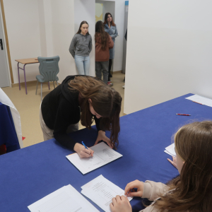 Uczennica kl. 8 pochylona nad listą uprawnionych do głosowania składa swój podpis.  Kliknięcie na zdjęcie spowoduje jego powiększenie do rozmiaru oryginalnego.
