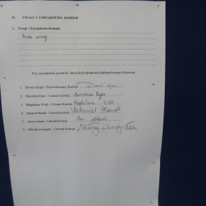 Część protokołu - kartka A4 zawieszona na sztaludze z niebieskim materiałem. Zawiera podpisy członków komisji. Kliknięcie na zdjęcie spowoduje jego powiększenie do rozmiaru oryginalnego.