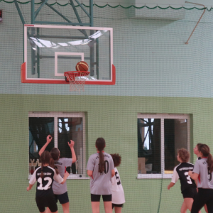 Uczestniczki zawodów w koszykówce rzucają piłką do kosza. Kliknięcie na zdjęcie spowoduje jego powiększenie do rozmiaru oryginalnego.