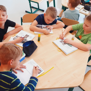 Chłopcy siedzą przy stolikach. Przygotowują prace w ramach innowacji pedagogicznej dotyczącej Brzeska i Okocimia. Kliknięcie na zdjęcie spowoduje jego powiększenie do rozmiaru oryginalnego.
