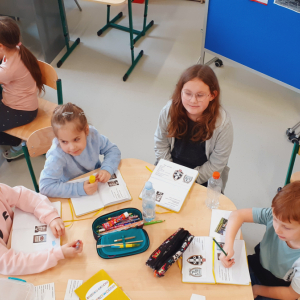 Uczniowie siedzą przy stolikach na świetlicy szkolnej. Przygotowują prace w ramach innowacji dotyczącej Brzeska i Okocimia. Kliknięcie na zdjęcie spowoduje jego powiększenie do rozmiaru oryginalnego.