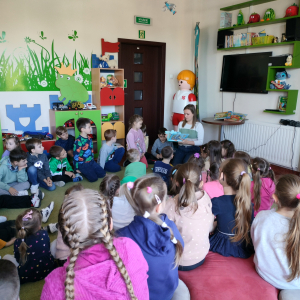 Pani bibliotekarka pokazuje przedszkolakom książkę. Dzieci siedzą w sali zabaw w brzeskiej bibliotece. Kliknięcie na zdjęcie spowoduje jego powiększenie do rozmiaru oryginalnego.