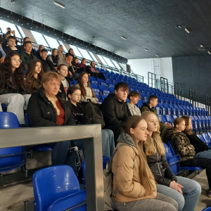 Młodzież z kl. 8 siedzi na trybunach w hali Akademii Wychowania Fizycznego w Krakowie.  Kliknięcie na zdjęcie spowoduje jego powiększenie do rozmiaru oryginalnego. 