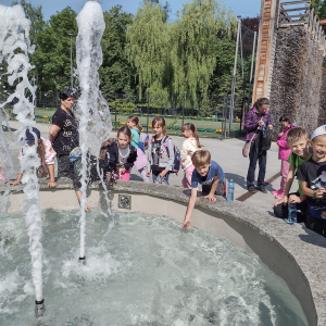 Dzieci z kl. 2 zanurzają ręce w fontannie znajdującej się na terenie tężni solankowej w Bochni. Towarzyszom im opiekunowie. Kliknięcie na zdjęcie spowoduje jego powiększenie do rozmiaru oryginalnego.