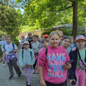 Uczniowie kl. 2 chodzą po alejkach w krakowskim ZOO. W tle zielone drzewa i krzewy. Kliknięcie na zdjęcie spowoduje jego powiększenie do rozmiaru oryginalnego.