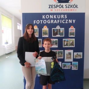 Szymon Sroka z kl. 4 a - laureat 1 miejsca w Szkolnym Konkursie Fotograficznym "Sport i przyroda". Towarzyszy mu pani Wicedyrektor Dorota Gurgul. W tle sztaluga z fotografiami wykonanymi przez uczniów kl. 4-8. Kliknięcie na zdjęcie spowoduje jego powiększenie do rozmiaru oryginalnego.