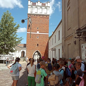 Młodzież na wycieczce na rynku w Sandomierzu. Przed nimi baszta. Kliknięcie na zdjęcie spowoduje jego powiększenie do rozmiaru oryginalnego.