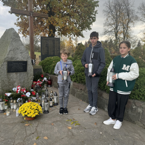 Przedstawiciele szkolnego Samorządu Uczniowskiego stoją przed mogiłą poległych żołnierzy. Kliknięcie na zdjęcie spowoduje jego powiększenie do rozmiaru oryginalnego.