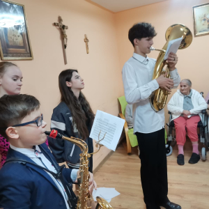 Przedstawiciele Zespołu Szkół w Szczurowej prezentują krótki program muzyczny w Domu Opieki Rodzinne Zacisze. Kliknięcie na zdjęcie spowoduje jego powiększenie do rozmiaru oryginalnego.