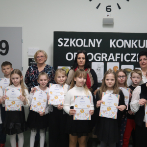 Uczniowie z kl. 2 i 3 biorący udział w Szkolnym Konkursie Ortograficznym w towarzystwie pani Dyrektor Joanny Ozorki-Krawczyk, Iwony Czesak i Stanisławy Bernady. W tle gazetka tematyczna dotycząca ortografii. Kliknięcie na zdjęcie spowoduje jego powiększenie do rozmiaru oryginalnego.