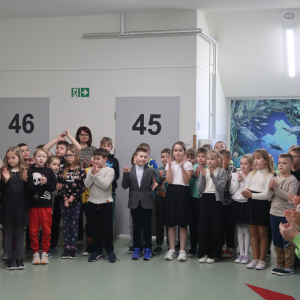 Uczniowie kl. 2 i 3 wraz z wychowawcami i nauczycielami zgromadzeni na szkolnym korytarzu w czasie wręczania nagród w Szkolnym Konkursie Ortograficznym. Kliknięcie na zdjęcie spowoduje jego powiększenie do rozmiaru oryginalnego.