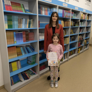 Amelia Cierniak wyróżniona za udział w akcji "Najlepszy czytelnik miesiąca kwietnia" w towarzystwie pani Wicedyrektor Doroty Gurgul. W tle regały z książkami. Kliknięcie na zdjęcie spowoduje jego powiększenie do rozmiaru oryginalnego.