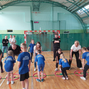 Rodzice stoją na przeciwko swoich dzieci. Wspólnie bawią się na hali sportowej w trakcie obchodów Dnia Rodziny. Kliknięcie na zdjęcie spowoduje jego powiększenie do rozmiaru oryginalnego.