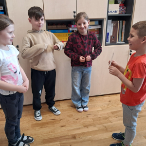 Dzieci stoją w kole i prezentują karty obrazkowe. Kliknięcie na zdjęcie spowoduje jego powiększenie do rozmiaru oryginalnego.