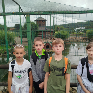 Grupka uczniów w Zwierzyńcu Dolnym. W tle klatki ze zwierzętami. Kliknięcie na zdjęcie spowoduje jego powiększenie do rozmiaru oryginalnego.