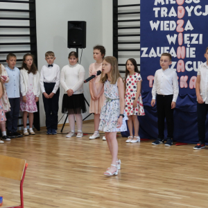 Jedna z dziewczynek prezentuje wiersz przygotowany dla rodziców. Kliknięcie na zdjęcie spowoduje jego powiększenie do rozmiaru oryginalnego.