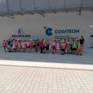 Dzieci przed ścianą Centrum Cogiteon w Krakowie w towarzystwie nauczycielki. Kliknięcie na zdjęcie spowoduje jego powiększenie do rozmiaru oryginalnego.
