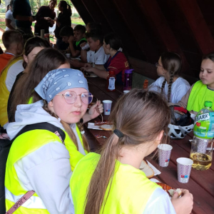 Szóstoklasiści spożywają kiełbaski na spotkaniu integracyjnym w lesie. Kliknięcie na zdjęcie spowoduje jego powiększenie do rozmiaru oryginalnego.