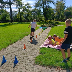 Chłopiec skacze pomiędzy kolorowymi słupkami w czasie zabaw integracyjnych na wyjeździe klas 5. Kliknięcie na zdjęcie spowoduje jego powiększenie do rozmiaru oryginalnego.