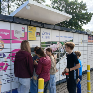 Klasa 7 stoi pod paczkomatem i sprawdza jak działa oprogramowanie paczkomatu. Kliknięcie na zdjęcie spowoduje jego powiększenie do rozmiaru oryginalnego.