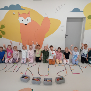 Wychowankowie świetlicy szkolnej z napisem "Dziękujemy" ułożonym z kredek, które otrzymali od starszych uczniów. Kliknięcie na zdjęcie spowoduje jego powiększenie do rozmiaru oryginalnego.