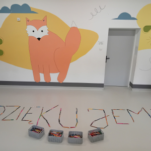 Napis z kredek ułożony na ziemi przez dzieci uczęszczające na świetlicę szkolną. Kliknięcie na zdjęcie spowoduje jego powiększenie do rozmiaru oryginalnego.
