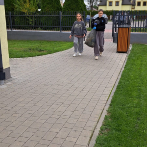 Dwie uczennice z kl. 6 a niosą worek ze śmieciami nazbieranymi w ramach Akcji Sprzątanie Świata 2025. Kliknięcie na zdjęcie spowoduje jego powiększenie do rozmiaru oryginalnego.