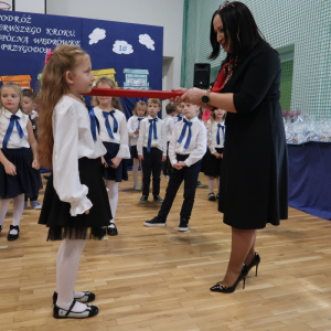 Pani Dyrektor Joanna Ozorka-Krawczyk pasuje kredką uczennicę klasy 1. Kliknięcie na zdjęcie spowoduje jego powiększenie do rozmiaru oryginalnego.