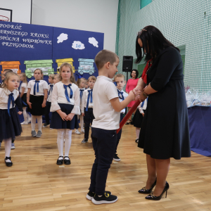 Pani Dyrektor Joanna Ozorka-Krawczyk gratuluje uczniowi klasy pierwszej pasownia na ucznia. Kliknięcie na zdjęcie spowoduje jego powiększenie do rozmiaru oryginalnego.